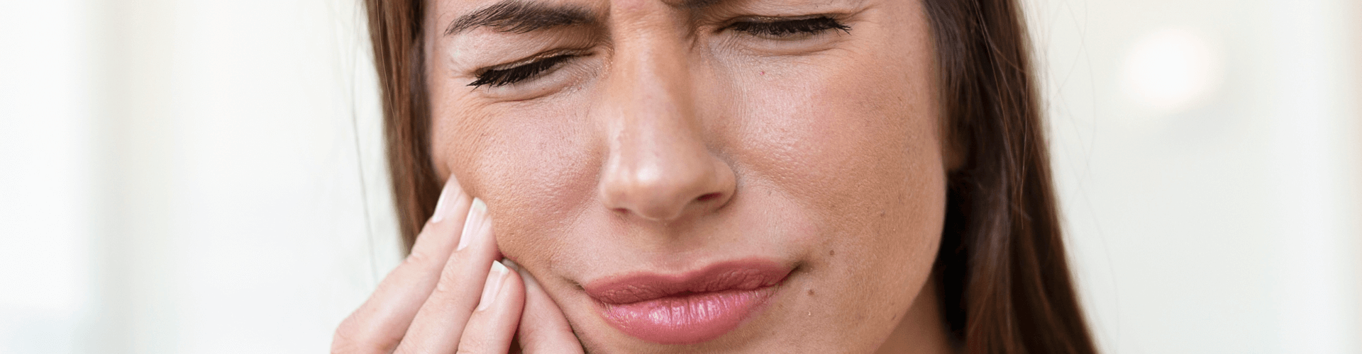Woman holding her cheek in pain.